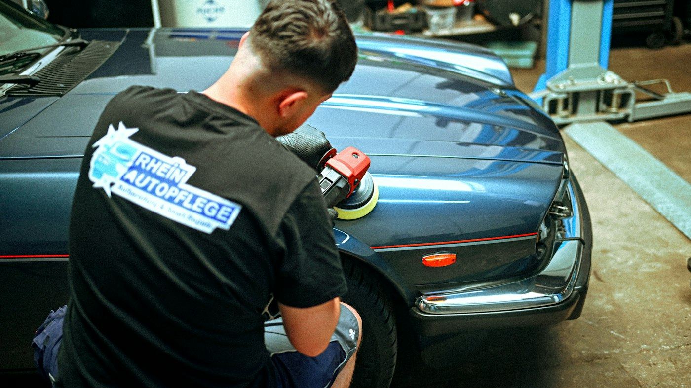 Polishing a blue classic car in the workshop